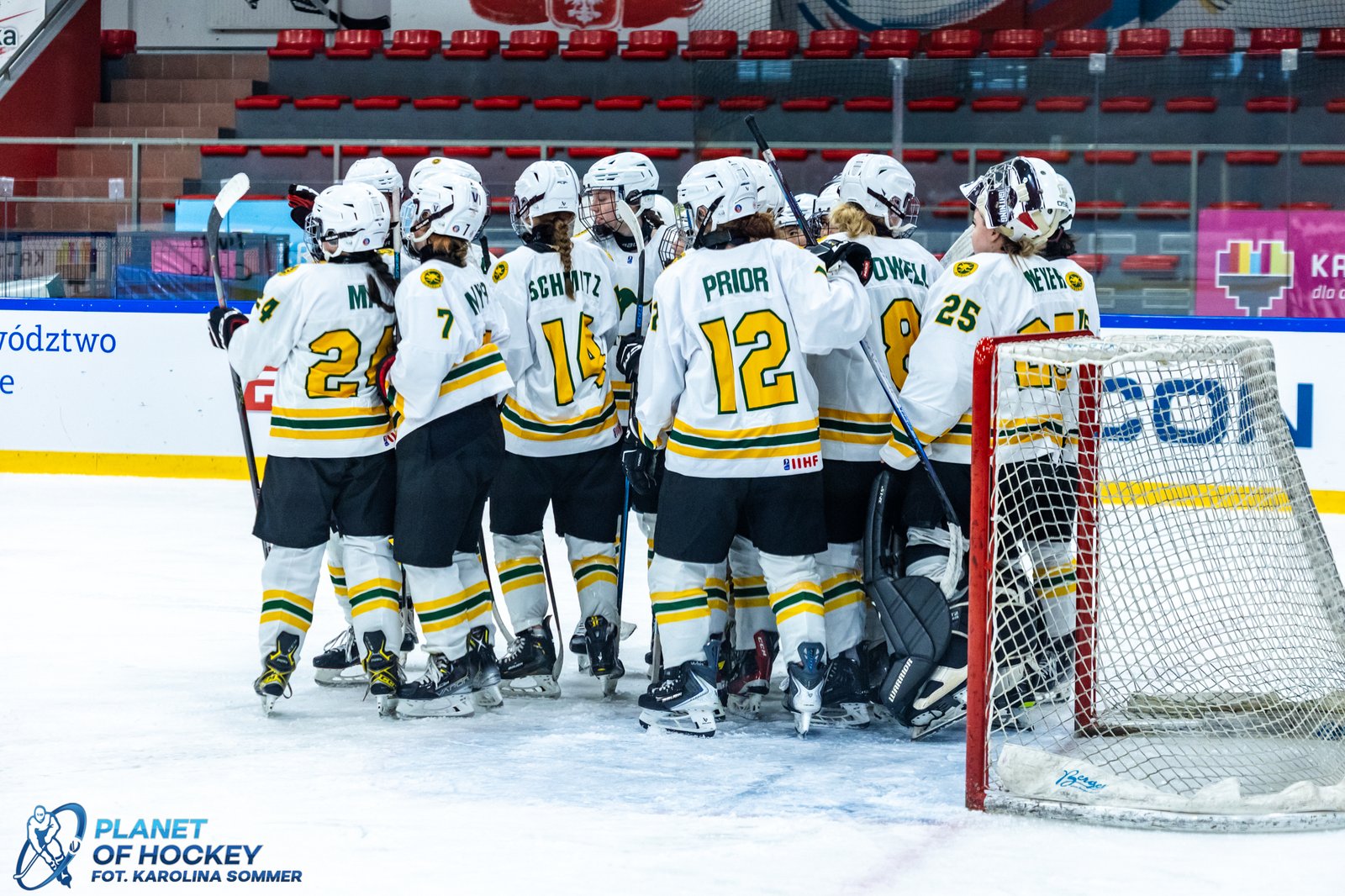 The Australia U18 Women’s Ice Hockey national team celebrates on the ice in their green and gold jerseys.