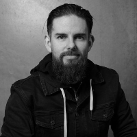 A black and white studio portrait of Seán Figgers, Video Producer for 6ix Dub Hockey, smiling slightly against a textured backdrop.
